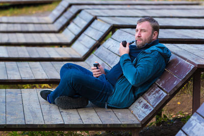 Mature man smoking while sitting on bench at park