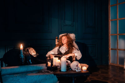 Young woman sitting on table against illuminated wall