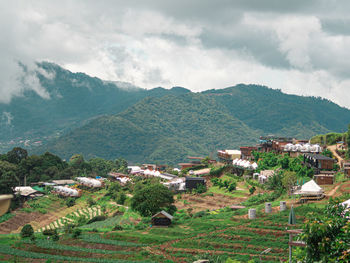 Scenic view of residential buildings by mountains against sky