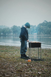 Woman preparing food on barbecue grill at lake