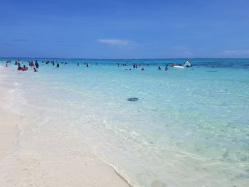 People at beach against blue sky