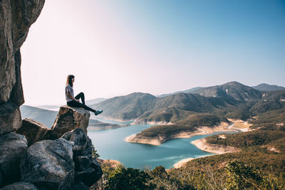 People looking at sea against mountain