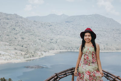 Portrait of young woman standing against mountain