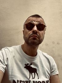 Portrait of man wearing sunglasses against wall