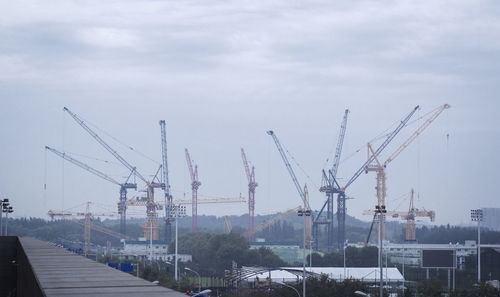 Cranes at construction site against sky