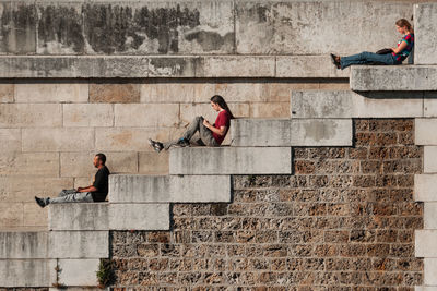 People sitting on staircase against wall