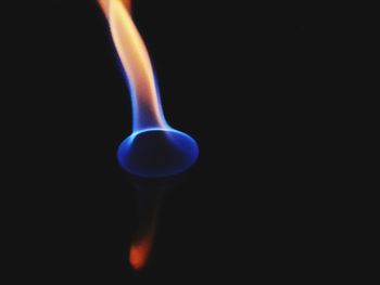 Close-up of burning candle against black background