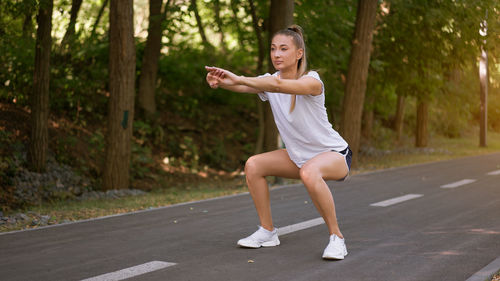 Full length of young woman using mobile phone on road