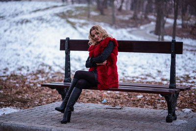 Woman sitting on bench in snow