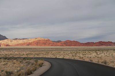 Road by desert against sky