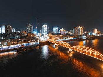 River amidst illuminated buildings against sky at night