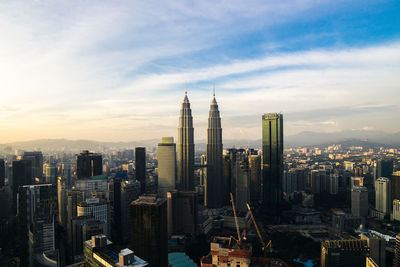 Aerial view of buildings in city against cloudy sky