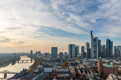 Aerial view of buildings in city against cloudy sky