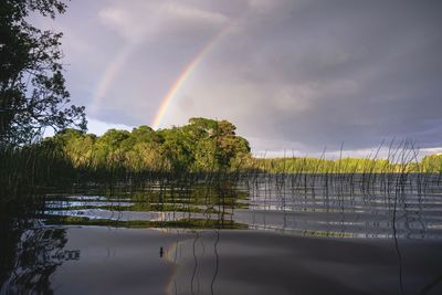 Scenic view of rainbow over lake against sky