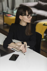 Thoughtful businesswoman with laptop sitting at office desk