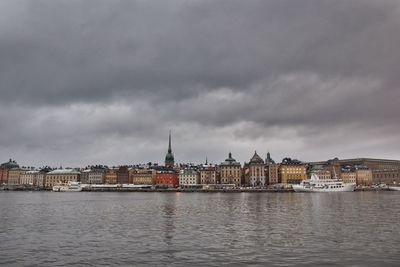 City at waterfront against cloudy sky