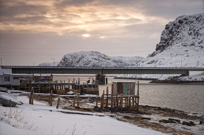 Built structure on snow covered mountain against sky during sunset