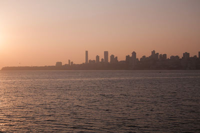 Scenic view of sea and buildings against sky during sunset