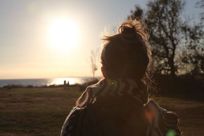 Rear view of woman on field against sky during sunset