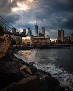 Sea by buildings against sky during sunset