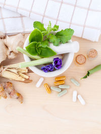 High angle view of herbs in spices with capsules on table