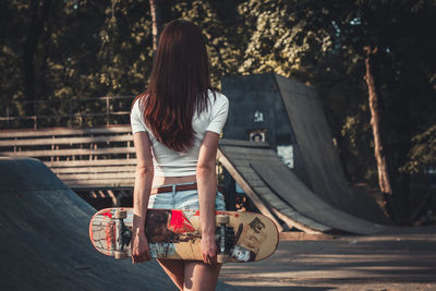 Rear view of woman standing against trees