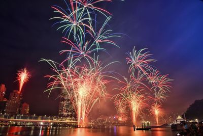 Firework display over river against sky at night