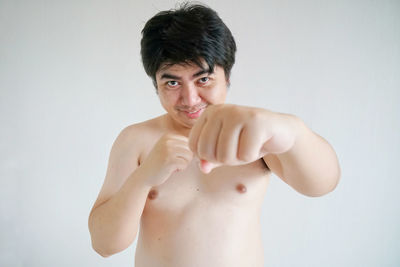 Portrait of young man standing against white background