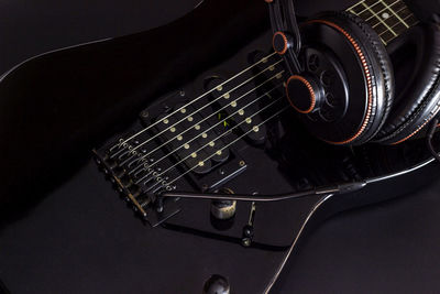 Close-up of guitar and headphones against black background