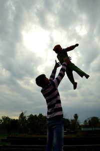 Low angle view of child standing against sky