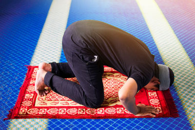 Rear view of man sitting on carpet