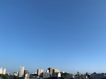 Buildings in city against clear blue sky
