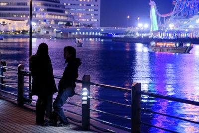 Rear view of people looking at illuminated city at night