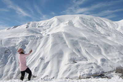 Man standing on snowcapped mountain against sky