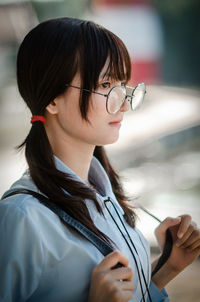 Portrait of young woman holding eyeglasses