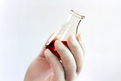 Close-up of woman hand holding bottle against white background