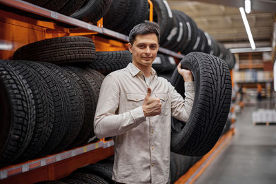 Portrait of man holding tire at store