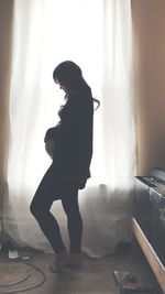 Side view of young woman standing at home