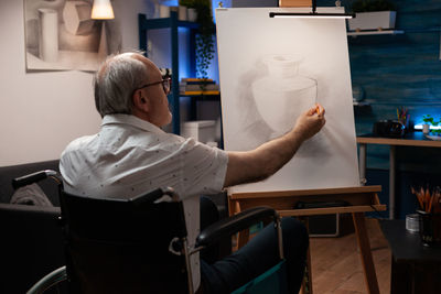 Man in wheelchair drawing on canvas