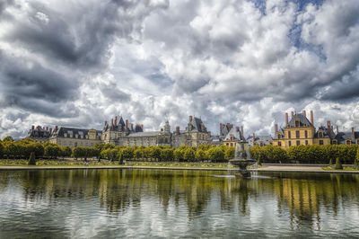 Fontainbleau reflecting in pond against cloudy sky