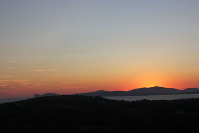 Scenic view of silhouette mountains against romantic sky at sunset