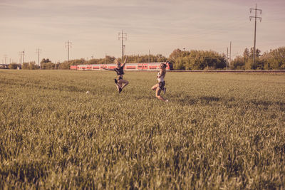 Friends enjoying on grassy field against sky