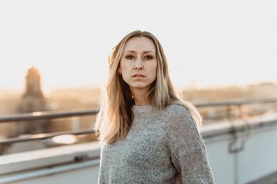 Portrait of beautiful young woman standing against sky