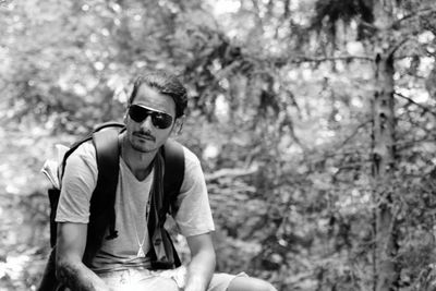 Man wearing sunglasses while sitting in forest