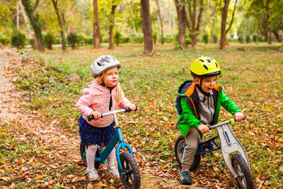 Siblings riding bicycle on autumn leaves