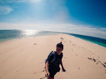 Man with monopod standing at beach against sky