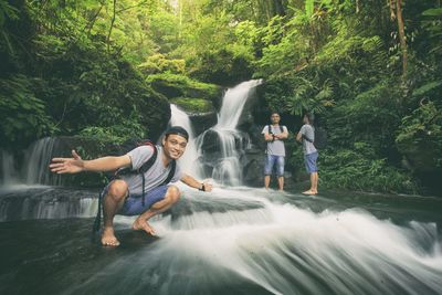 Multiple image of man by waterfall in forest