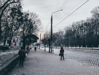 Rear view of people walking on street in city