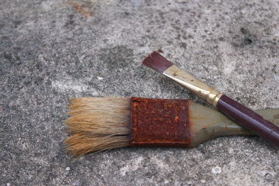 High angle view of rusty paintbrushes on ground