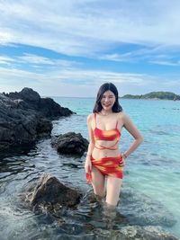 Rear view of woman standing in sea against sky